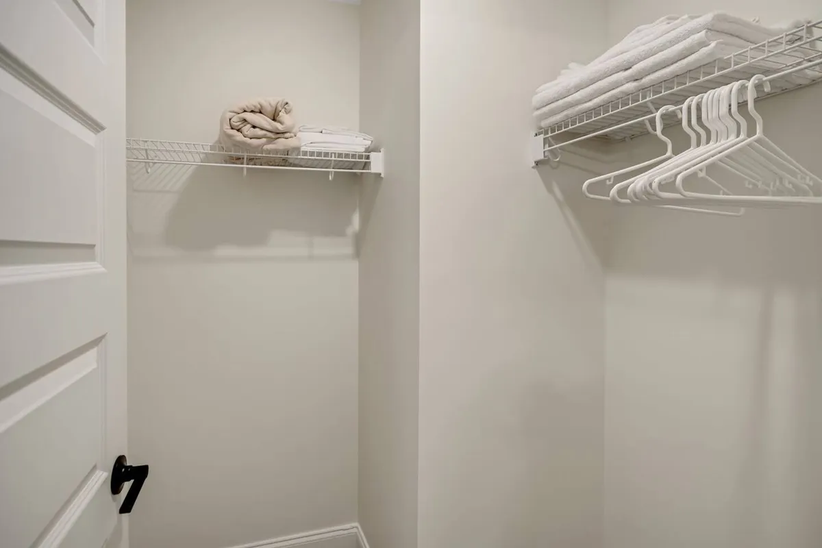 Open shelving neatly stacked with plush towels and hangers, set in a tidy, organized closet space. The simple, clean arrangement radiates a sense of order and hospitality, suggesting readiness for recreational routines.
