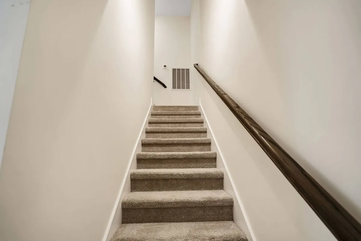 An interior shot of a bright staircase and handrail, capturing the movement between levels inside the home. The mood is uplifting, hinting at the anticipation of daily activities and transitions.